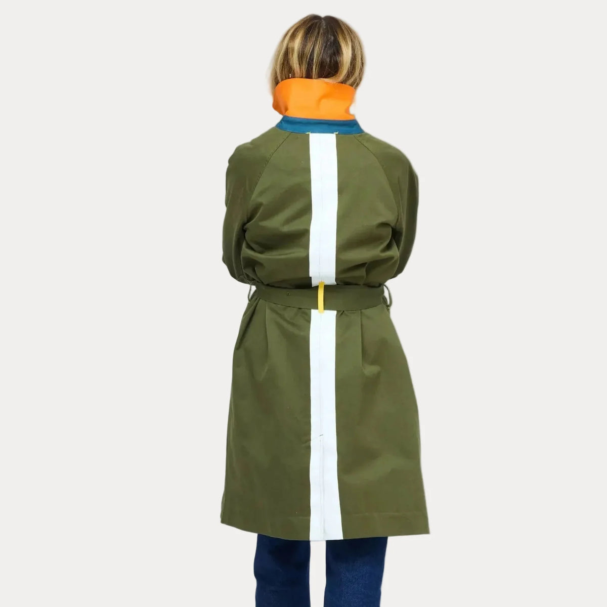 Kerri Rosenthal olive trench with white stripe and orange collar, shown styled with blue jeans.