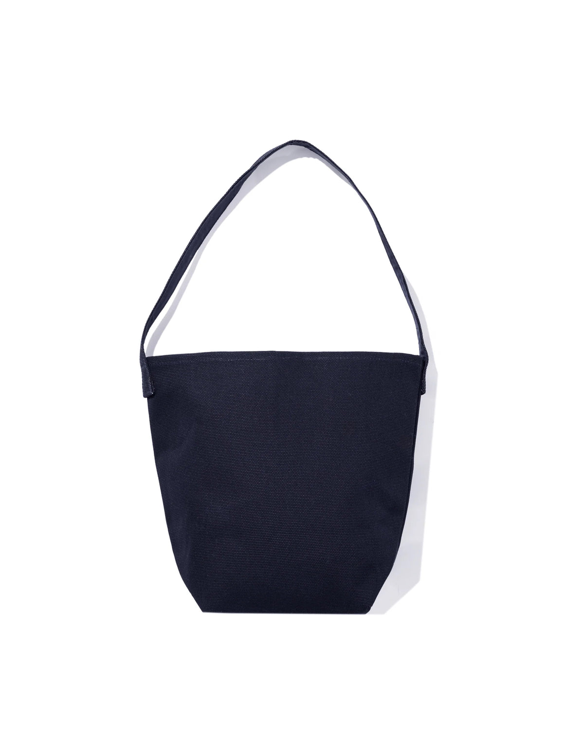 The Uma by Kule is a simple, dark navy blue cotton canvas bucket bag with a single shoulder strap, shown on a white background.