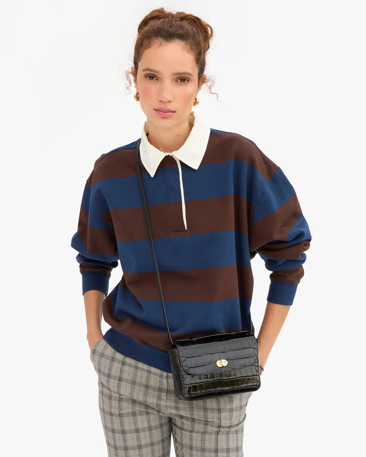 Black croco-embossed Italian leather Kathryn crossbody bag by Clare Vivier worn with a striped polo.