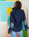 Keaton Denim Shirt by Kerri Rosenthal with heart elbow patches, shown from the back, abstract art setting.