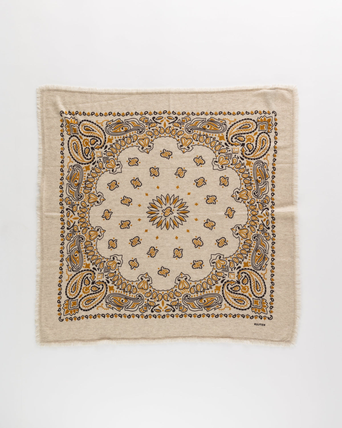 The KUJTEN Hachiko Scarf is a square beige accessory made from printed cashmere, showcasing a yellow and black paisley design with a central starburst, shown flat against a white background.