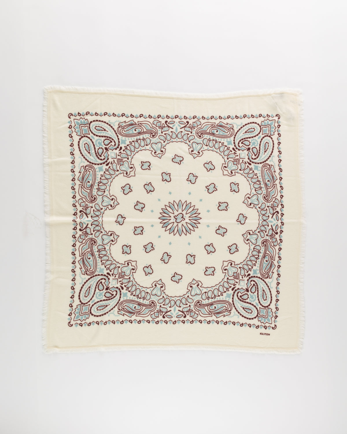 The Hachiko Scarf by KUJTEN is a cream cashmere square with an intricate brown and teal paisley-floral print, central sunburst motif, and fringed edges.