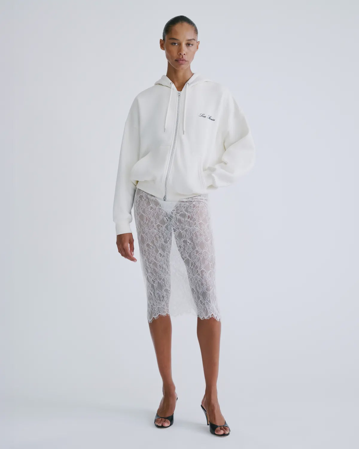 MIA white hoodie by Love Stories styled with lace skirt and black heels, minimal background for a modern look.
