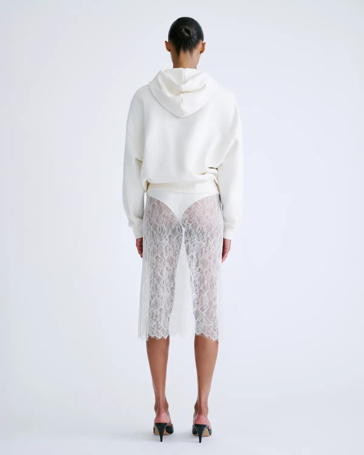 White hoodie and lace skirt from Love Stories, featuring a modern layered look styled with black heels.