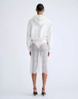 White hoodie and lace skirt from Love Stories, featuring a modern layered look styled with black heels.