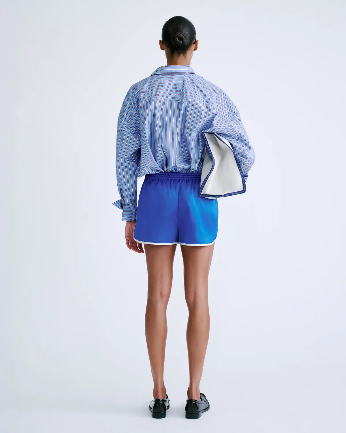 FRANKIE mid-waist shorts by Love Stories in a casual lifestyle setting with blue striped shirt, white clutch under arm.