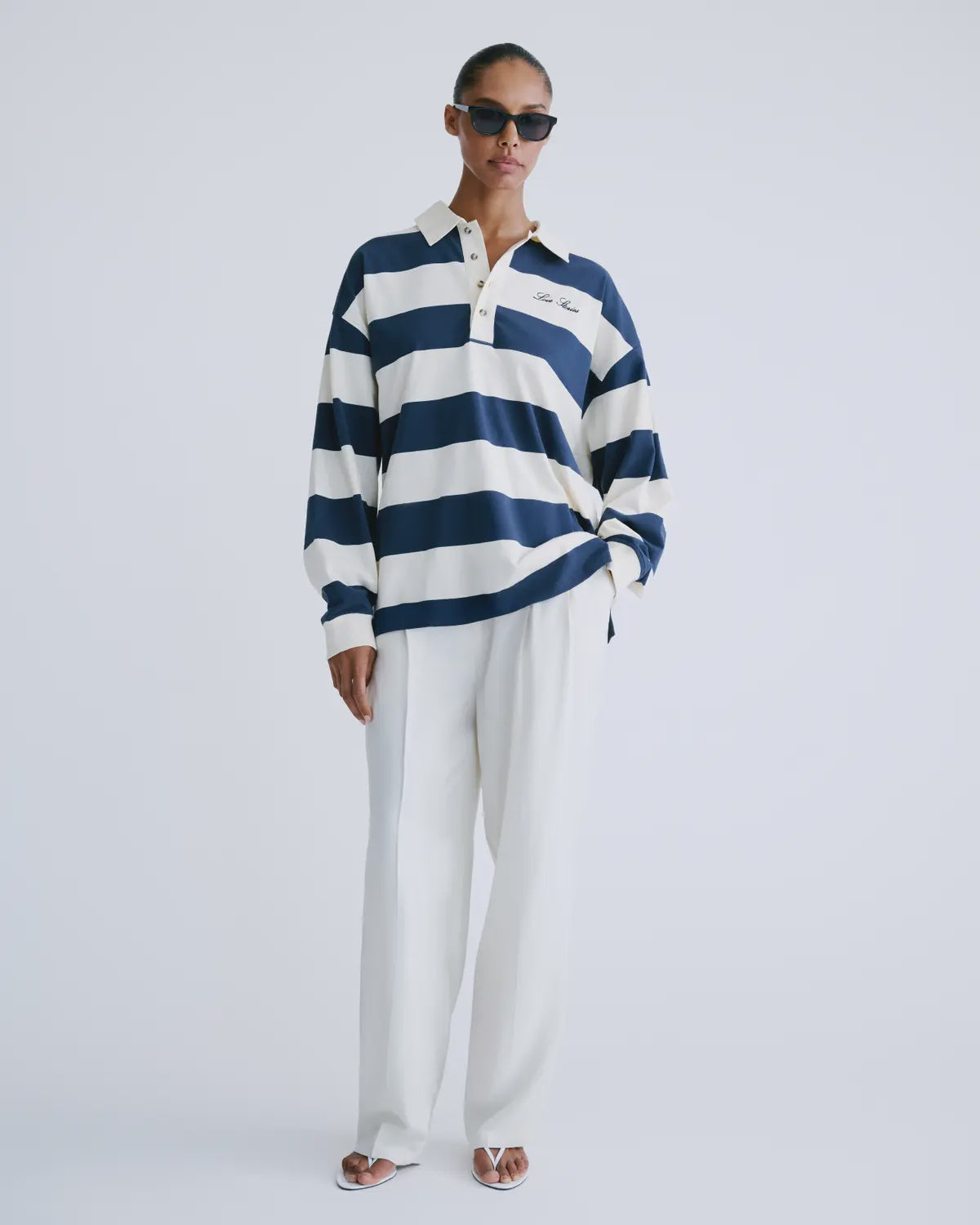 Striped cotton rugby shirt by Love Stories styled with white pants and sandals, relaxed hand-in-pocket look.