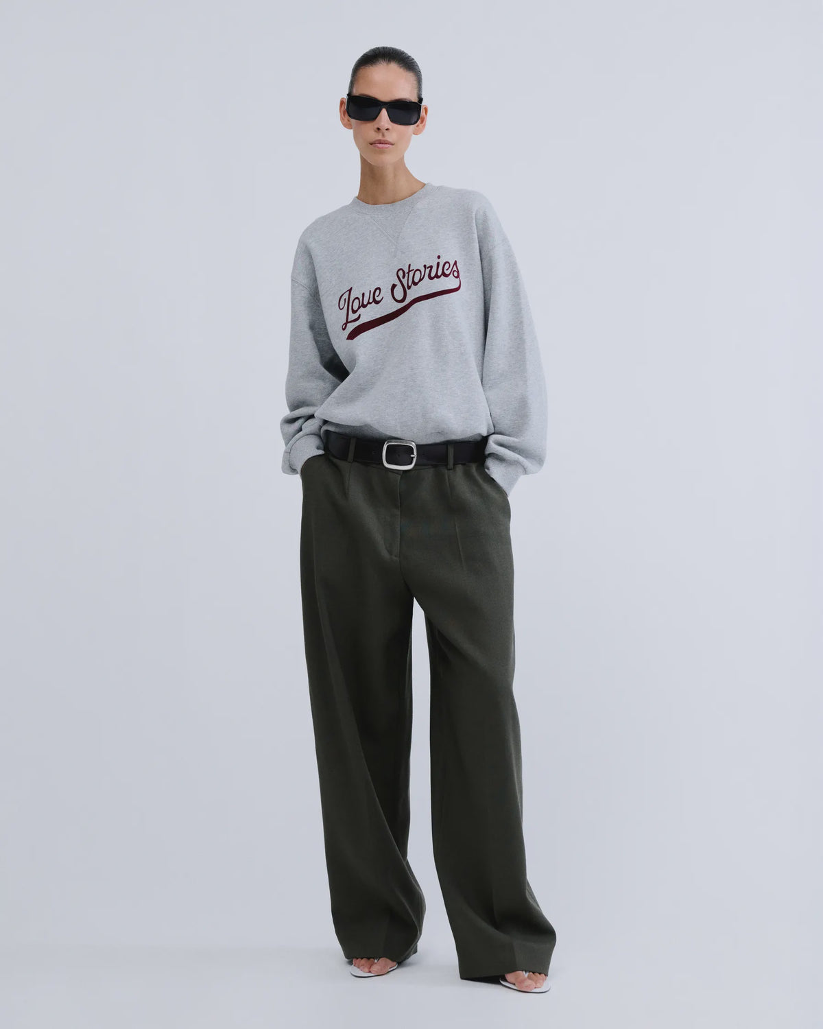 Grey knit sweater by SLOANE Love Stories with wide-leg dark green pants, black belt, sunglasses, and sandals.