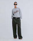 Grey knit sweater by SLOANE Love Stories with wide-leg dark green pants, black belt, sunglasses, and sandals.
