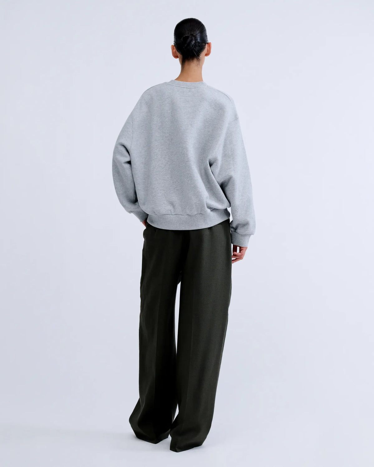 SLOANE Love Stories sweater in dark, relaxed fit, styled with loose pants; minimalist neutral background.