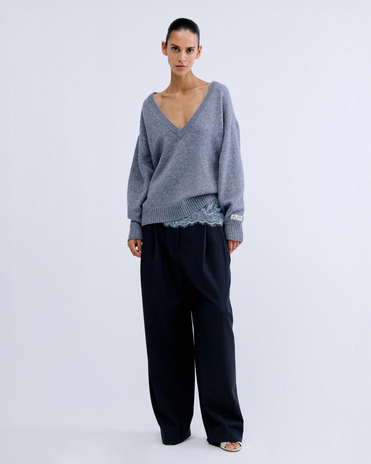 Love Stories RACHEL jumper in grey worn over a pale blue lace camisole with wide-leg dark trousers.