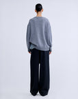RACHEL white wool blend crewneck sweater with light blue lace hem worn over dark wide-leg trousers, back view.