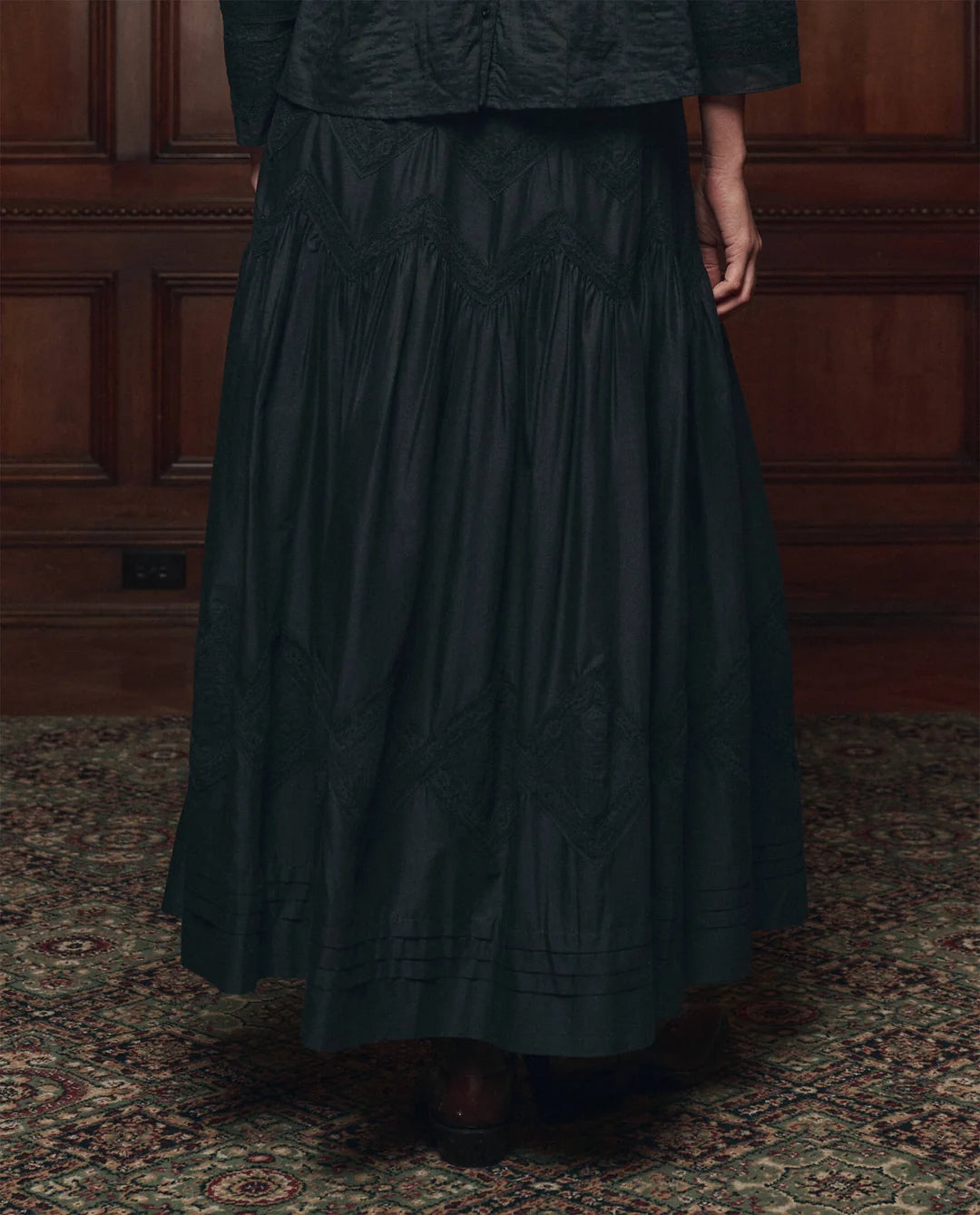 Pleated Victorian-style Lattice Lace skirt by The Great Inc., patterned detail, shown with wood panel backdrop.