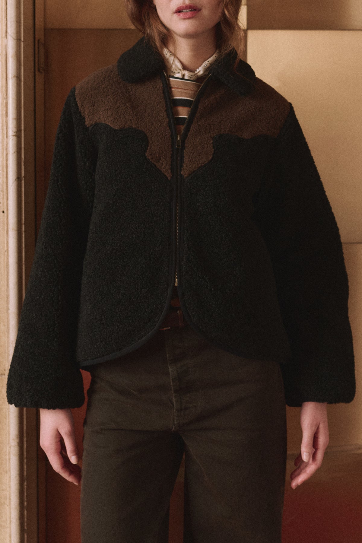 The Great Inc. Reversible Western Yoke Pasture Jacket layered over a striped shirt, styled indoors.