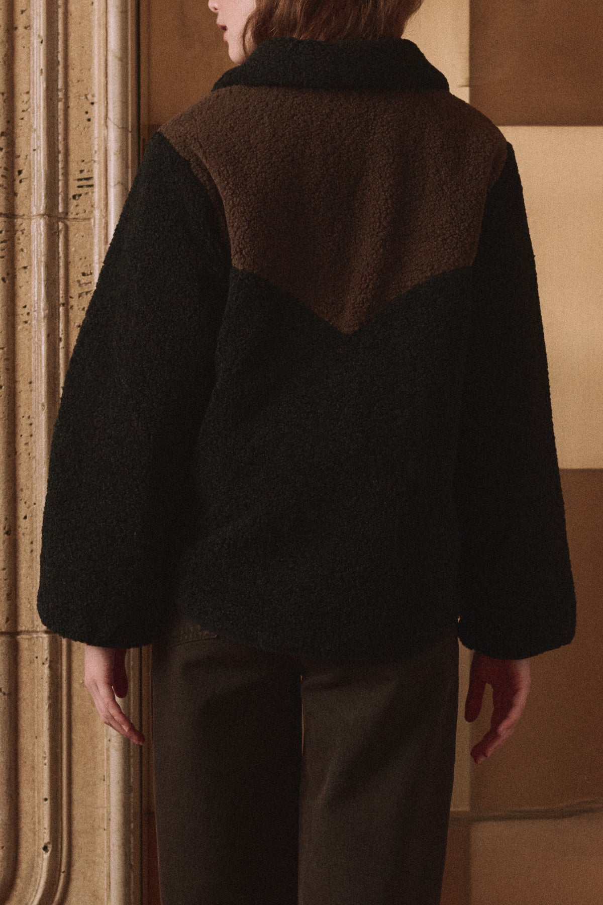 Reversible Western Yoke Pasture Jacket by The Great Inc., back view with patterned wall backdrop.