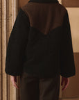 Reversible Western Yoke Pasture Jacket by The Great Inc., back view with patterned wall backdrop.