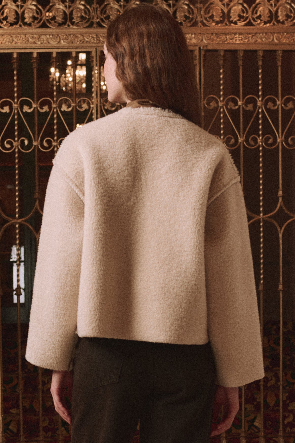 Woodside Toggle Coat by The Great Inc. in a relaxed style, shown near ornate gold gates with hair down.