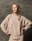The Rehearsal Sweatshirt by The Great Inc. in a casual fit, modeled standing with hands on hips.