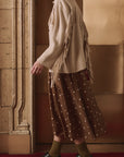 Western Fringe Sweater Jacket by The Great Inc. styled with a polka dot skirt on a red carpet backdrop.