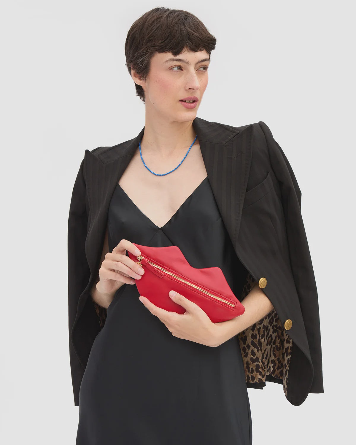 Clare Vivier Lips Flat Clutch in red with gold zipper held by model.