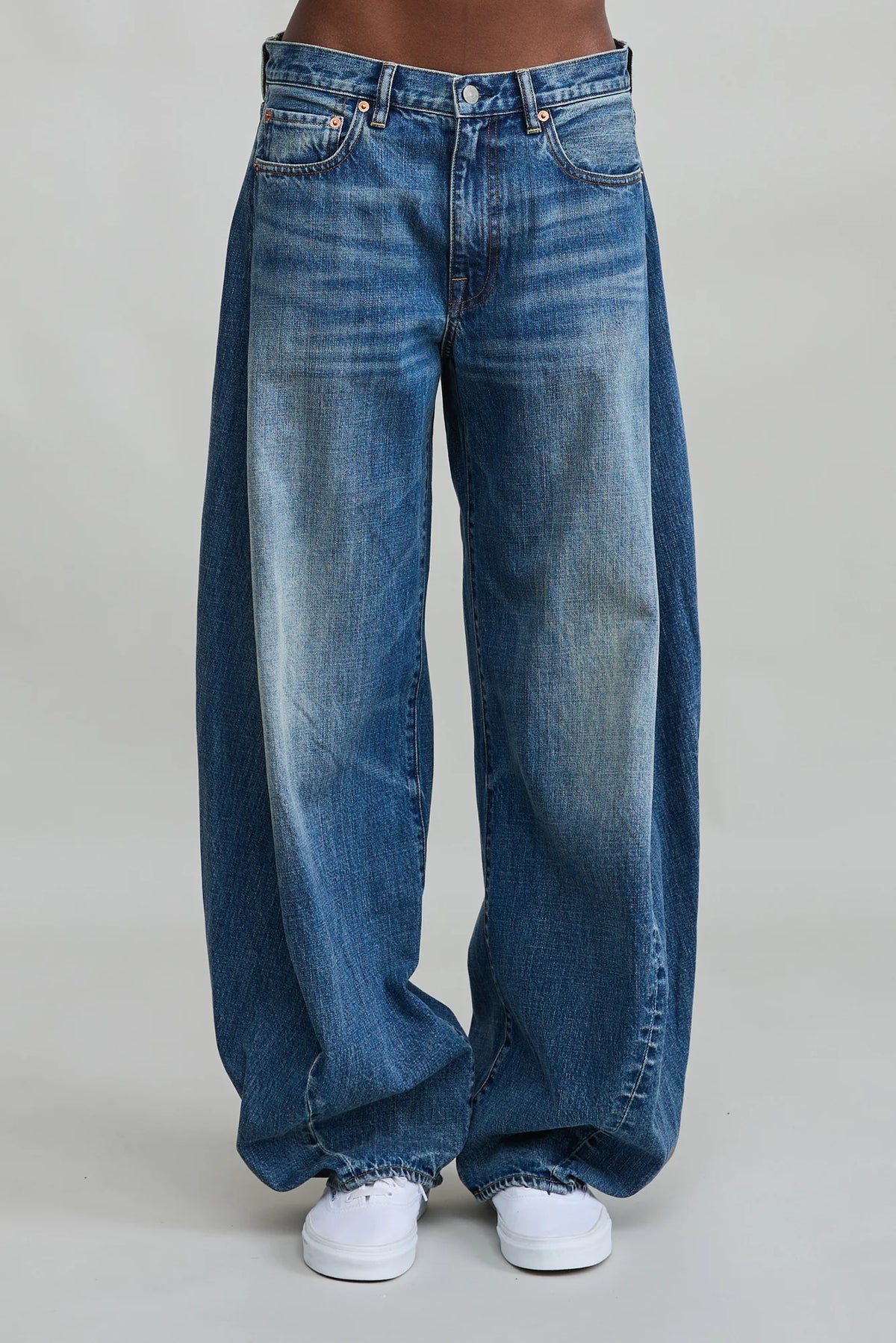 Indigo denim REMY BARREL JEAN by Denimist styled with white sneakers, shown against a gray backdrop.