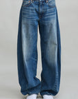 Indigo denim REMY BARREL JEAN by Denimist styled with white sneakers, shown against a gray backdrop.