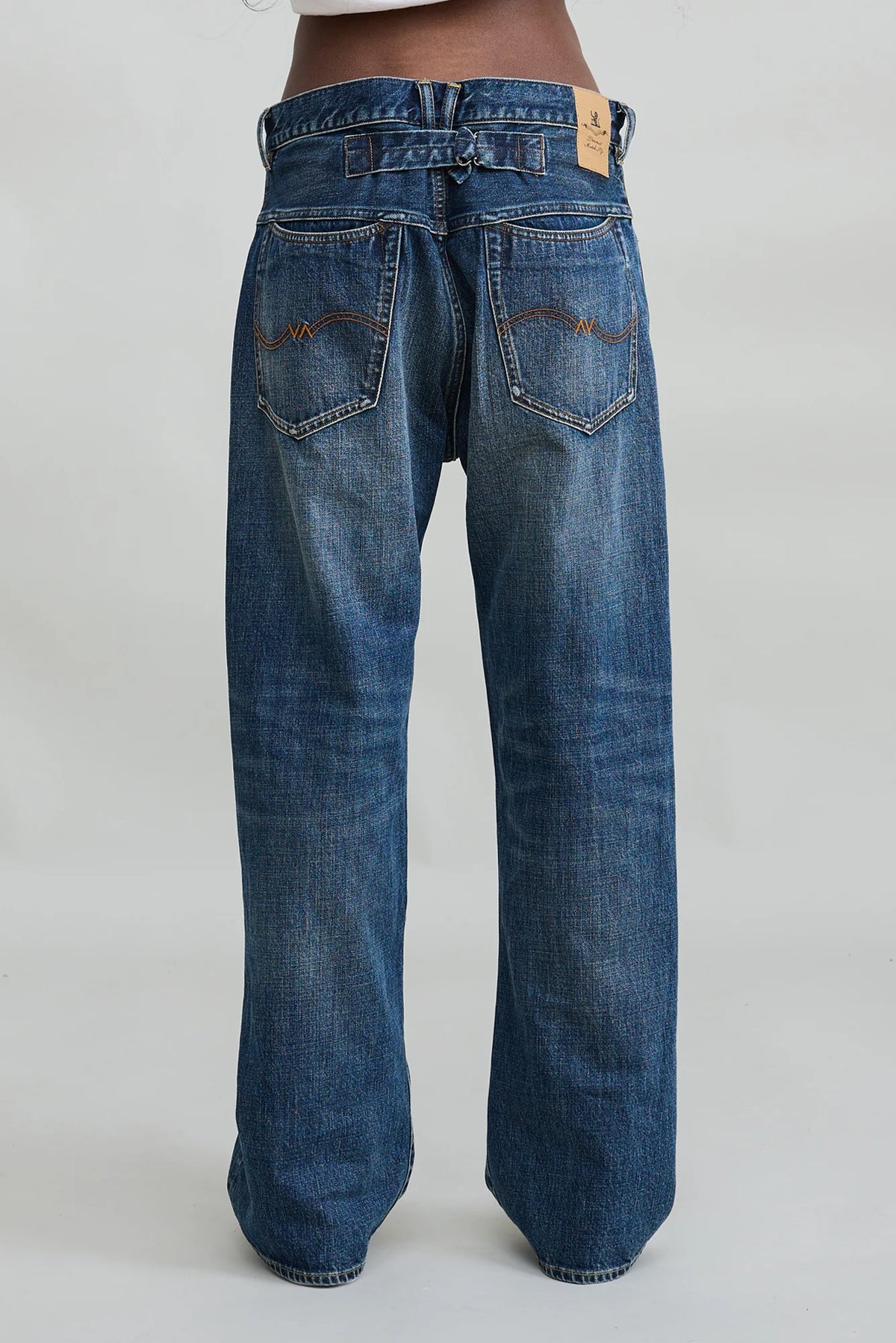 Loose indigo denim jeans with brown tag and visible pockets, back view; Denimist ALLFIT JEAN at Bungalow.