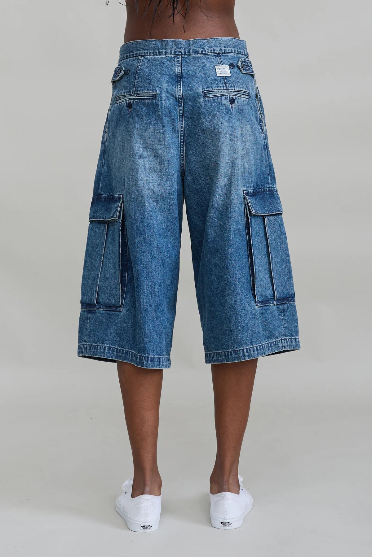 AINSLEY TRIPLE PLEAT CARGO SHORTS by Denimist with oversized flap pockets, shown from the back with white slip-ons.