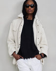Denimist Utility Field Jacket in cream worn over a black sweater and white jeans.