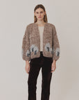 Maiami Fleecy Alpaca Intarsia Bomber Cardi in beige and grey worn over a beige top and dark brown trousers.
