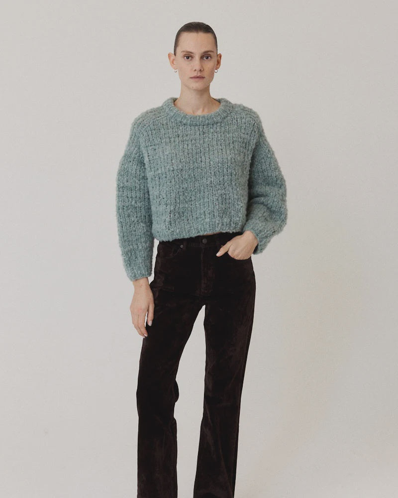 Fuzzy light blue Maiami Wool Alpaca Mix Cropped Pullover worn with dark brown trousers.