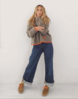 Kerri Rosenthal Marley Cashmere Sweater in taupe with neon orange trim and heart detail paired with blue jeans.