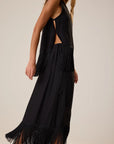Sleeveless black Anita Skirt by Natalie Martin with fringe hem and side slit, shown in a modern lifestyle setting.