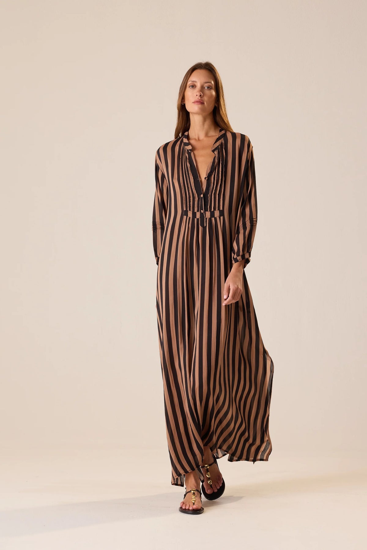 Brown and black striped maxi dress with v-neck by Natalie Martin, modeled against a light background.