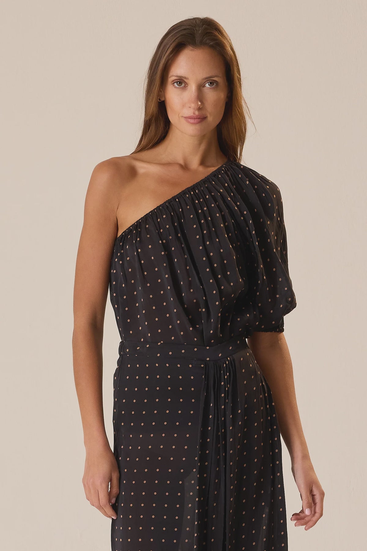 Black polka dot one-shoulder Erin Top by Natalie Martin, 70s-inspired style shown on model against plain background.