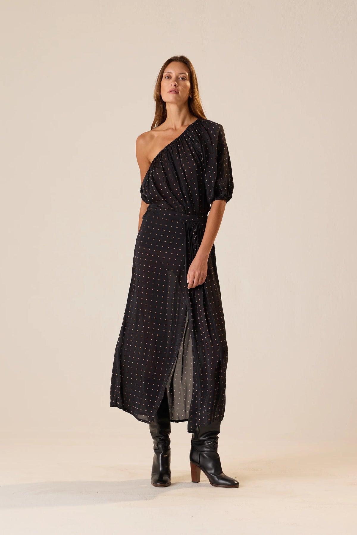 Erin Top by Natalie Martin in sheer black polka dot, 70s-inspired one-shoulder style paired with boots.