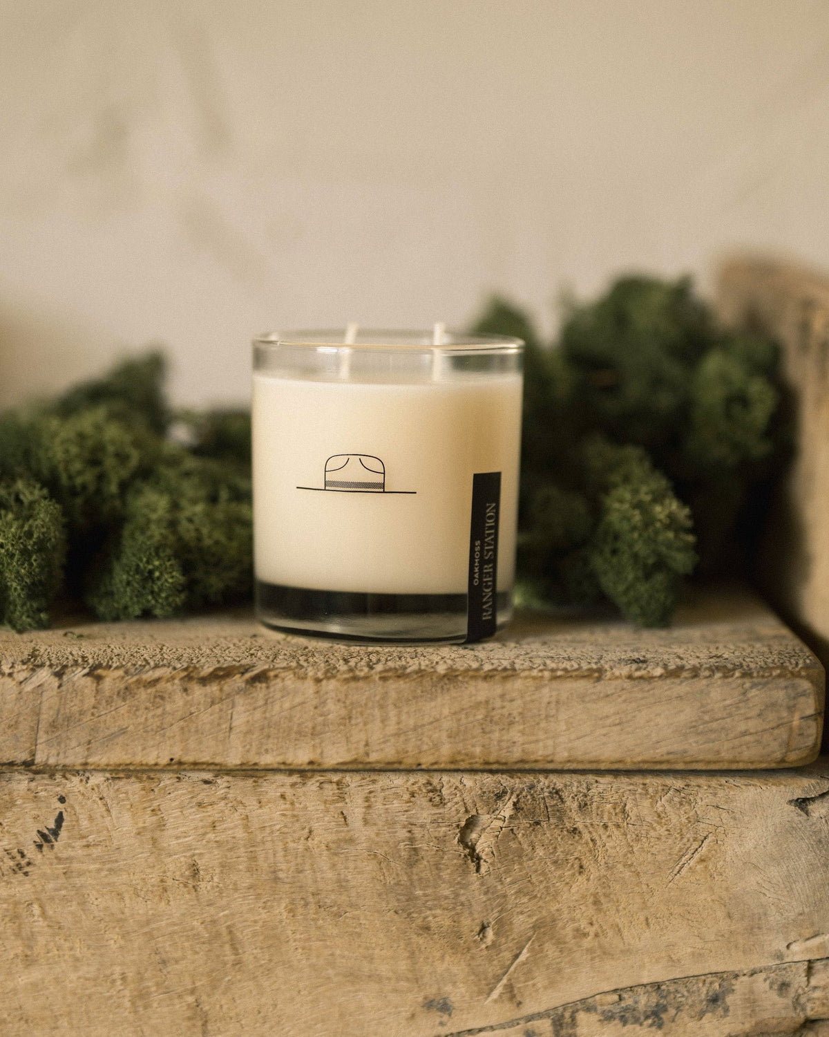 Faire Oak Moss candle in a clear glass jar on a rustic wooden shelf with moss accents.