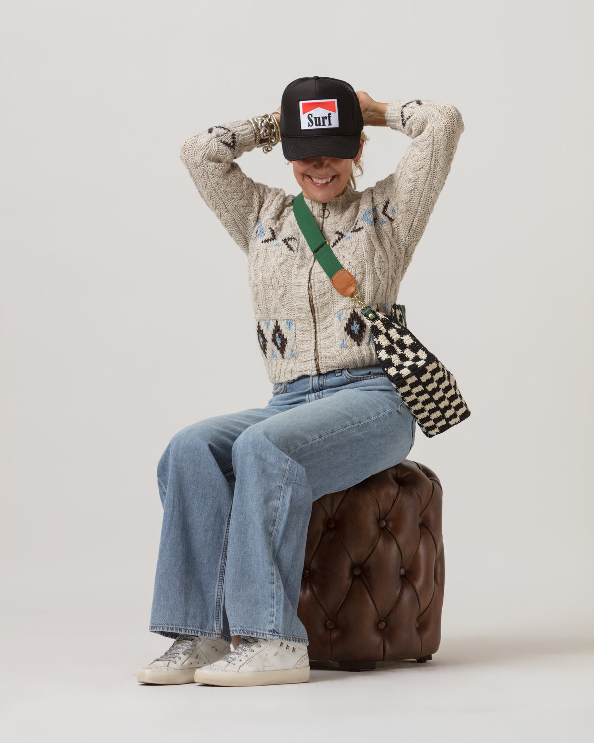 Cozy jeans and sweater style with casual hat, styled on a brown stool for a relaxed Bungalow Furniture vibe.