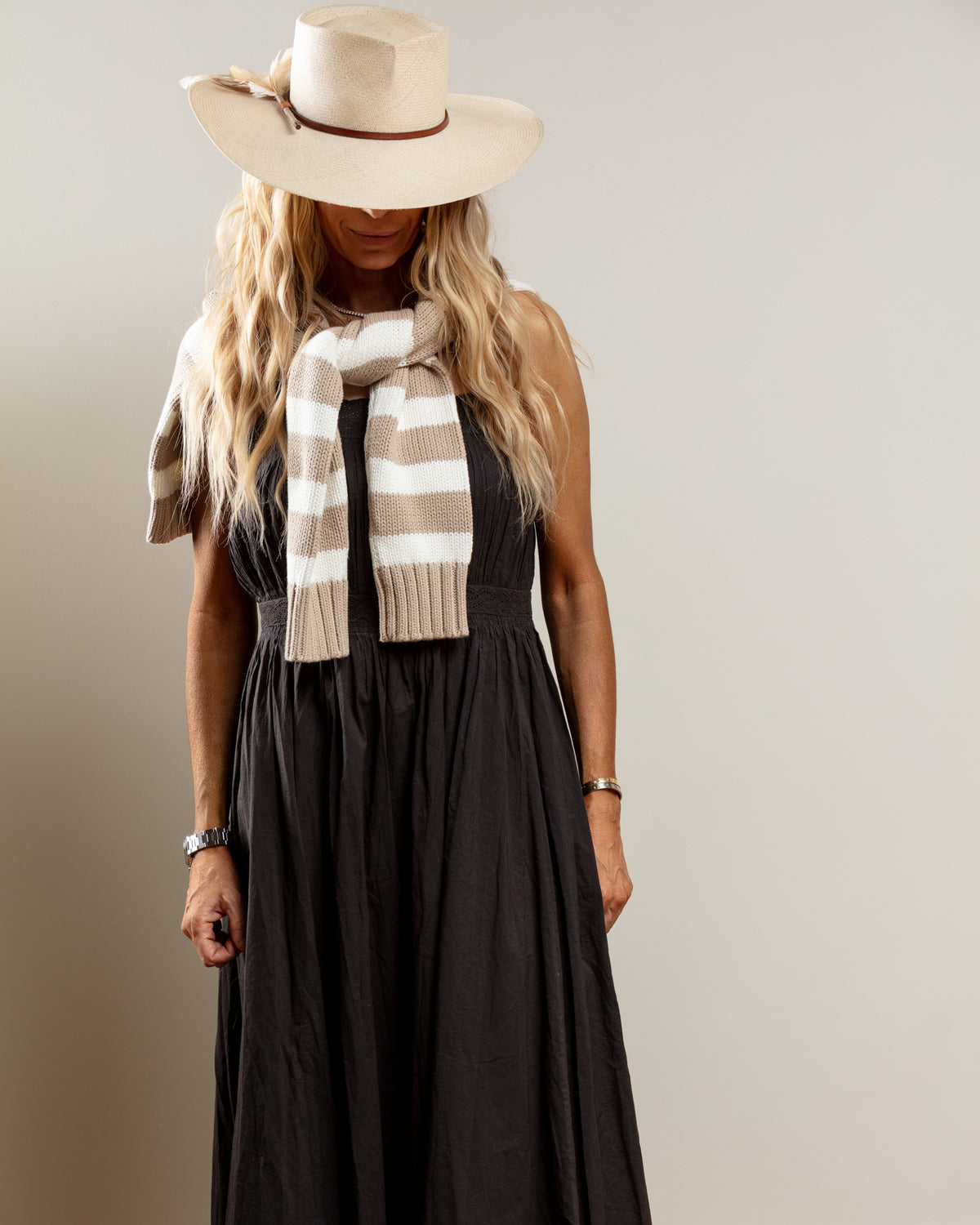 Black dress and hat styled with striped sweater over shoulders, classic look for Bungalow Furniture & Accessories collection.