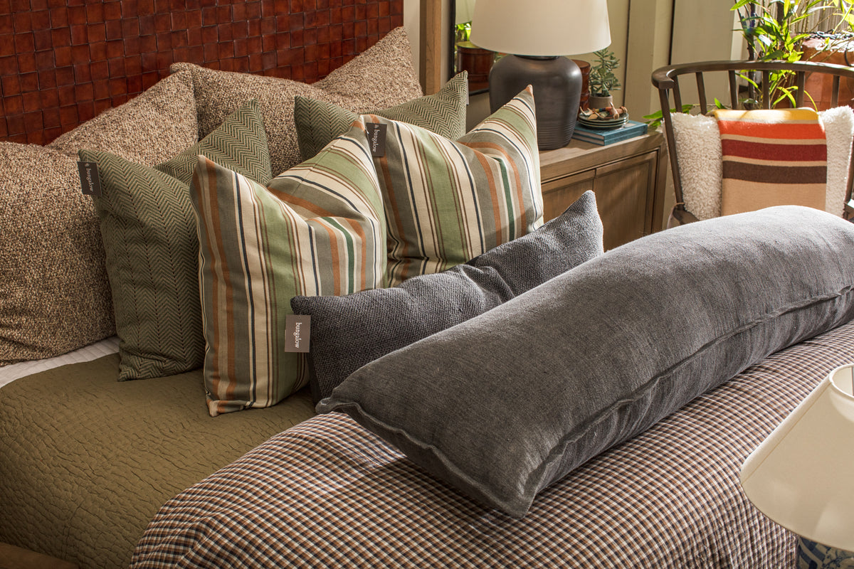 Bungalow Furniture bed with striped pillows, gray bolster, and nightstand in a cozy modern bedroom setting.