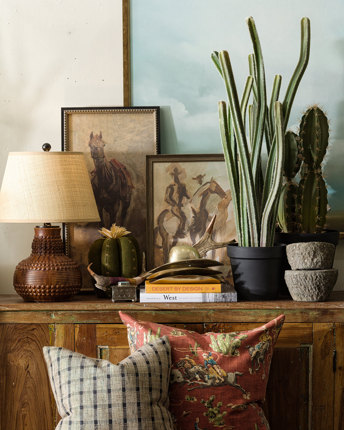 Boho pillows on a rustic table styled with books, cacti, and art for a cozy Bungalow Furniture living space.