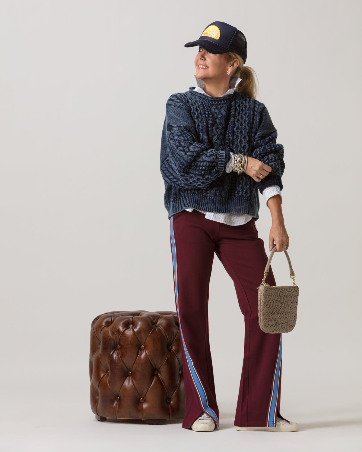 Modern ottoman in brown leather beside a woman in casual attire, styled for a relaxed living room setting.