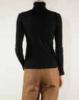 Black Pharaoh Cleo Turtleneck in lightweight rib, back view, styled with brown pants by Bungalow Furniture & Accessories.