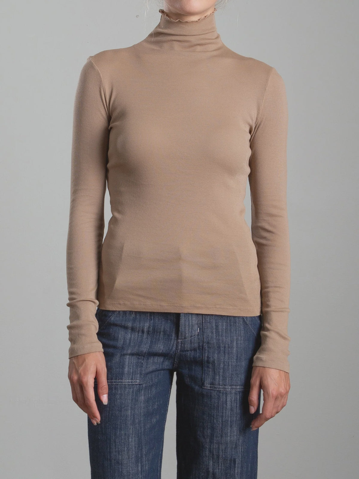 Beige Pharaoh’s Cleo Turtleneck by Bungalow Furniture in lightweight rib, styled with blue jeans, gray background.
