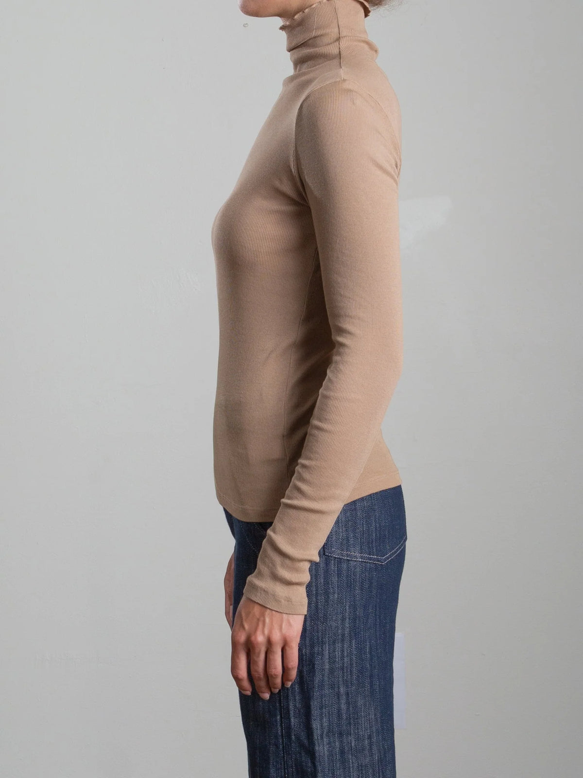 Beige Pharaoh Cleo Turtleneck in lightweight rib by Bungalow, styled with blue jeans against a plain backdrop.