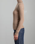 Beige Pharaoh Cleo Turtleneck in lightweight rib by Bungalow, styled with blue jeans against a plain backdrop.