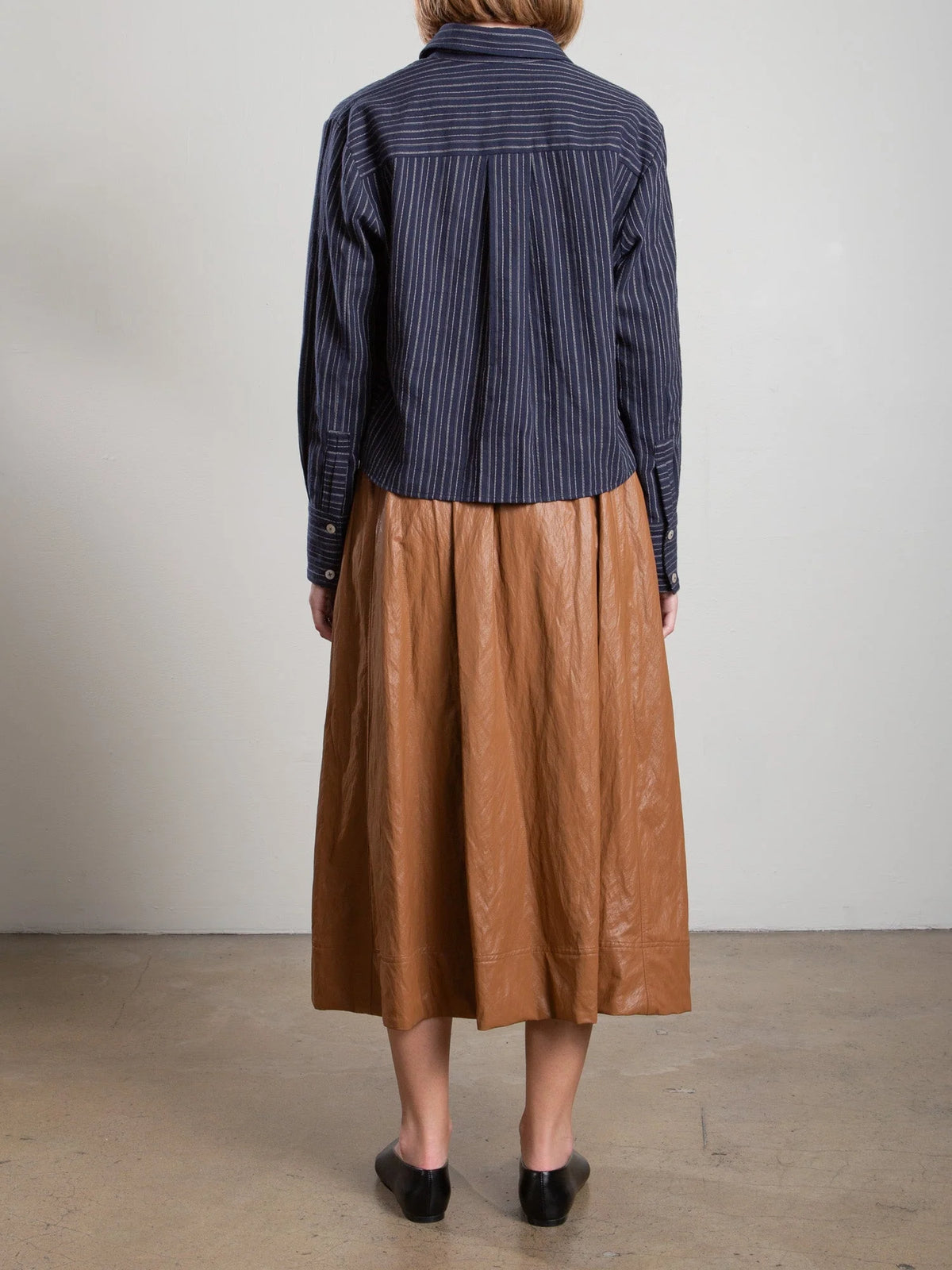 Pharaoh Claudia Skirt with faux leather pockets styled with a striped shirt and black shoes in a modern indoor setting.