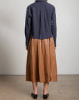 Pharaoh Claudia Skirt with faux leather pockets styled with a striped shirt and black shoes in a modern indoor setting.