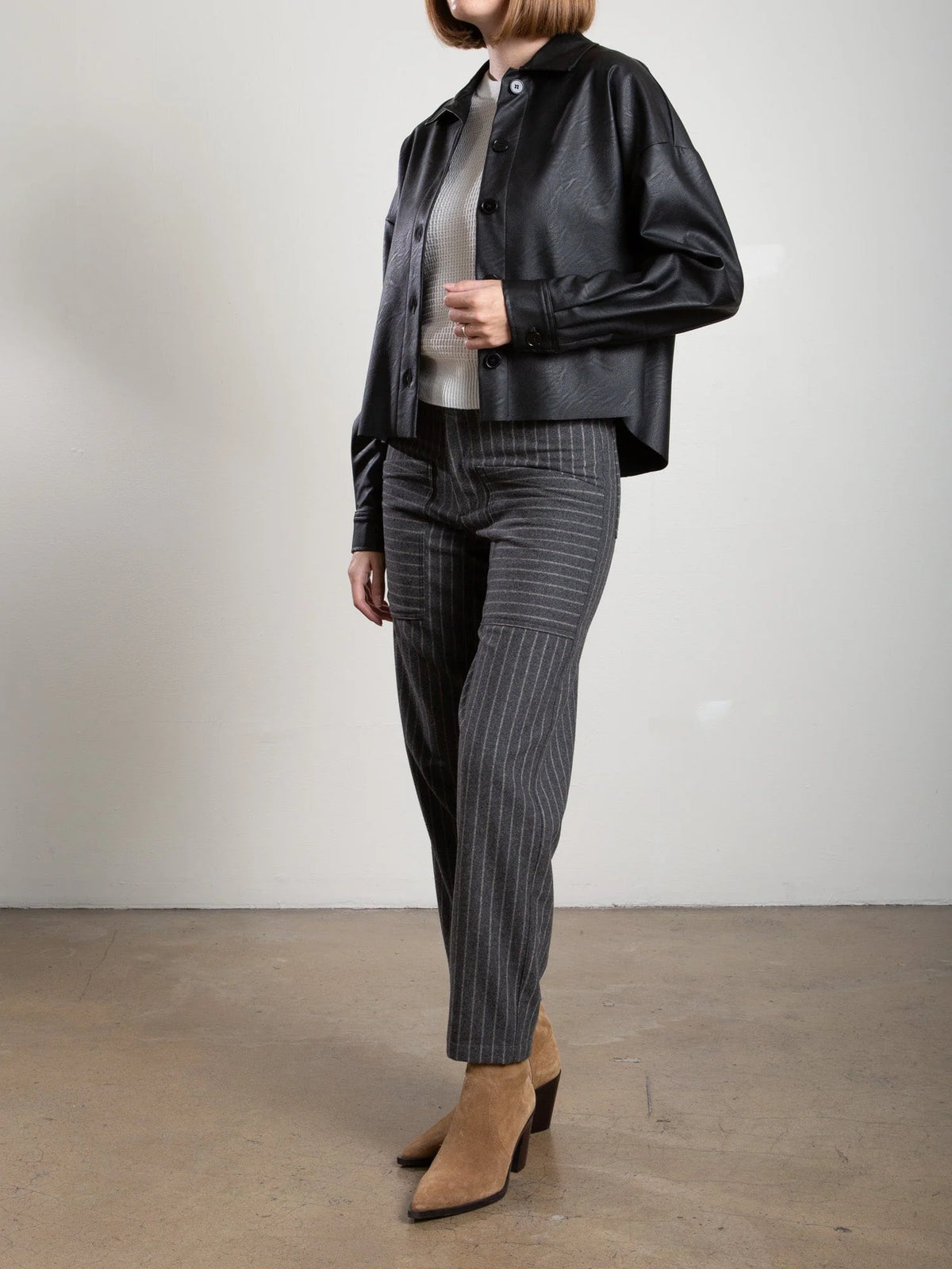 Pharaoh Ezra Pant in gray wool pinstripe worn with a white sweater and black jacket.