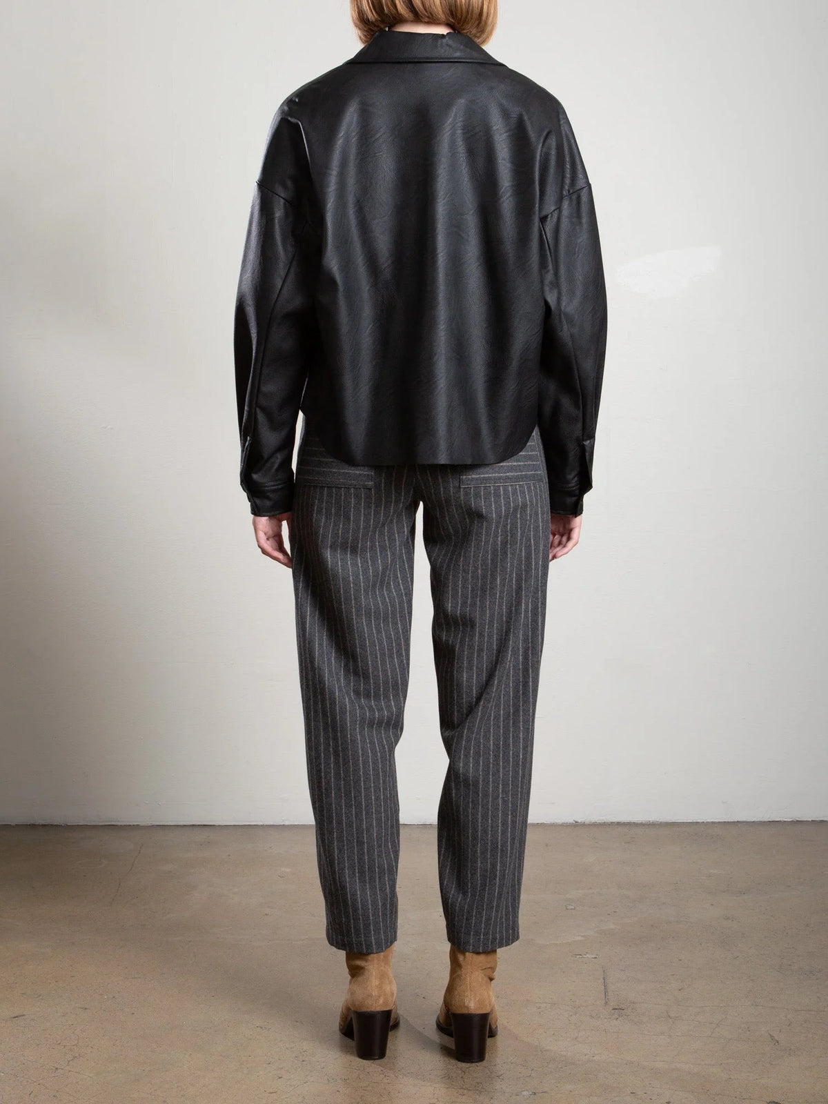 Ezra Pant in grey wool pinstripe with drawstring waist, styled with a black jacket and tan heeled boots.